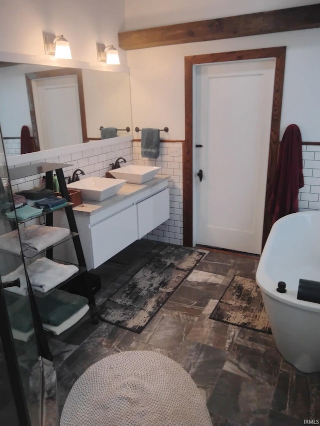 3417 Parkway S Dr, Indianapolis, IN 46201 - bathroom featuring double vanity, tile walls, a freestanding tub, and a wainscoted wall