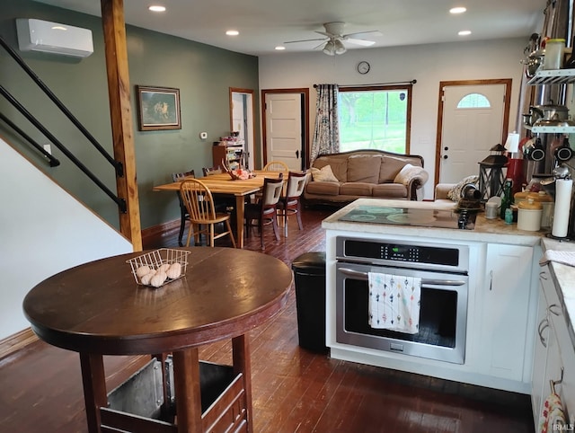 3417 Parkway S Dr, Indianapolis, IN 46201 - kitchen featuring stainless steel oven, black electric cooktop, a wall mounted air conditioner, white cabinetry, and dark wood-type flooring