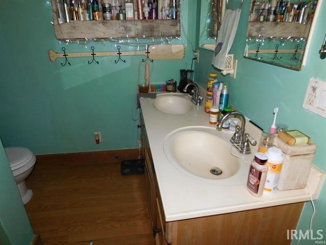 225 N Parker Ave, Albany, IN 47320 - bathroom featuring double vanity, toilet, and wood finished floors