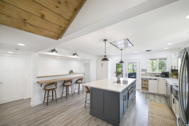 11721 N Elm Grove Dr, Syracuse, IN 46567 - kitchen featuring a breakfast bar, light wood-style floors, light countertops, hanging light fixtures, and recessed lighting
