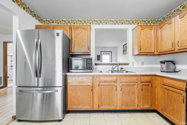 4736 Anglers Ln, Fort Wayne, IN 46808 - kitchen with freestanding refrigerator, a sink, light countertops, and brown cabinets