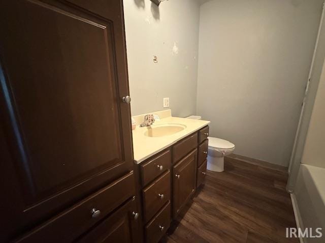 401 E Sycamore St, Converse, IN 46919 - bathroom with toilet, wood finished floors, vanity, a tub to relax in, and baseboards
