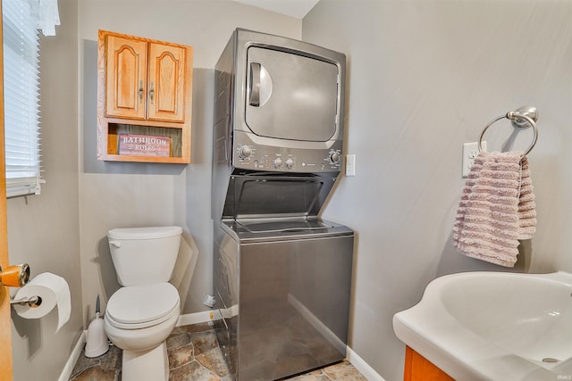 1402 Tanager Dr, Warsaw, IN 46580 - half bathroom featuring stacked washer / drying machine, baseboards, toilet, stone finish floors, and vanity