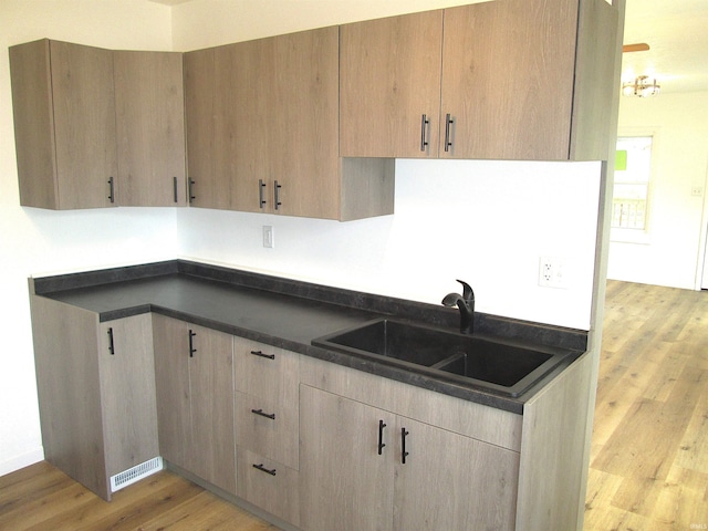 712 Hubbard St, Mishawaka, IN 46544 - kitchen featuring dark countertops, light wood finished floors, a sink, and light brown cabinetry