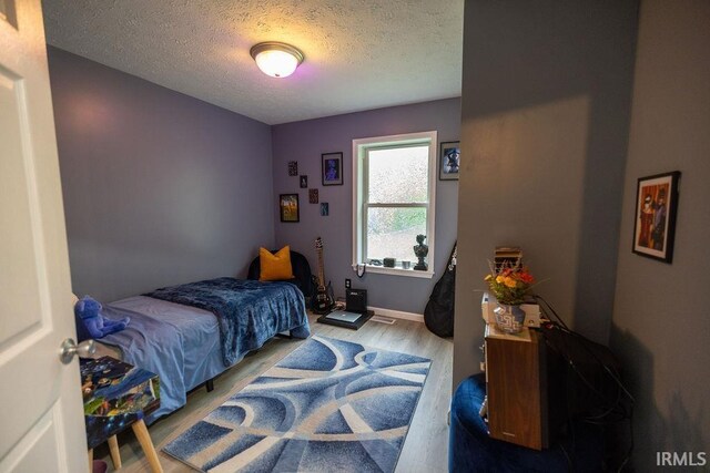 509 N Mckenzie St, Muncie, IN 47304 - bedroom featuring light wood-style flooring, a textured ceiling, and baseboards