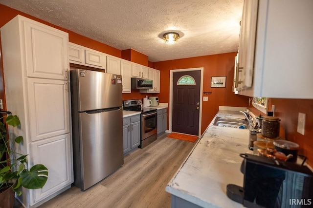 509 N Mckenzie St, Muncie, IN 47304 - kitchen with appliances with stainless steel finishes, a sink, light wood finished floors, light countertops, and a textured ceiling