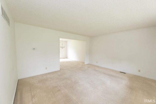 1005 S Carleton Ct, Bloomington, IN 47401 - unfurnished room featuring light colored carpet, a textured ceiling, and a chandelier
