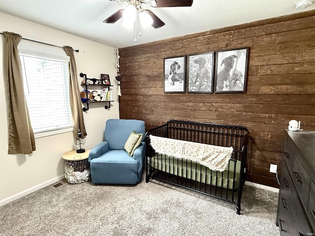310 Main St, Lagro, IN 46941 - carpeted bedroom featuring wooden walls, a nursery area, baseboards, and a ceiling fan