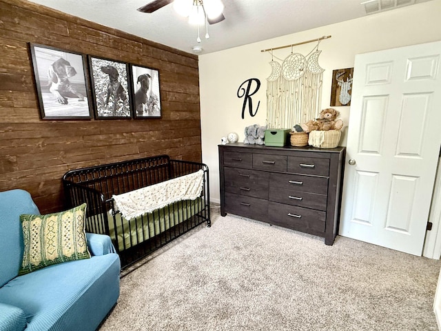 310 Main St, Lagro, IN 46941 - bedroom with wood walls, light carpet, a nursery area, and ceiling fan