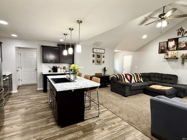 310 Main St, Lagro, IN 46941 - kitchen featuring a sink, open floor plan, a kitchen bar, wood finished floors, and a center island with sink