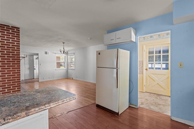 1725 W Saxon Dr, Marion, IN 46952 - kitchen with freestanding refrigerator, wood-type flooring, a chandelier, baseboards, and white cabinets