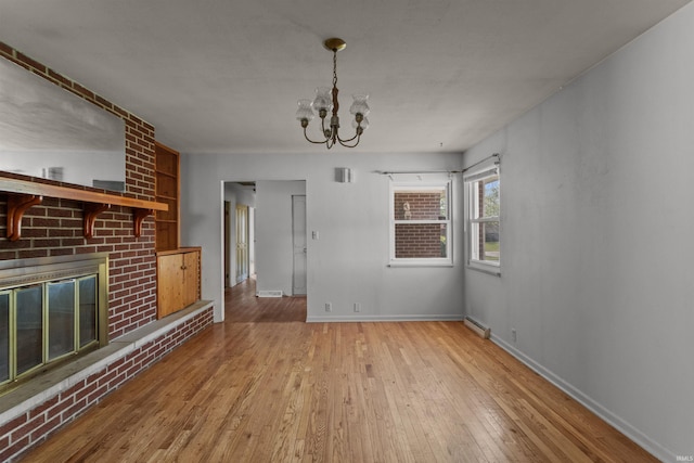1725 W Saxon Dr, Marion, IN 46952 - unfurnished living room with a chandelier, hardwood / wood-style flooring, a brick fireplace, baseboards, and baseboard heating