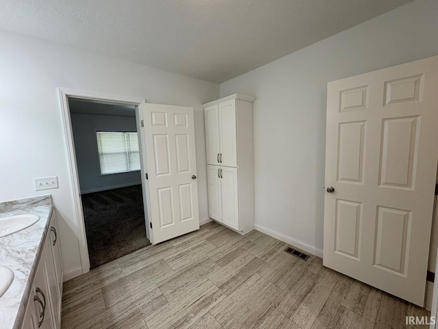 844 Ben Franklin St, Cloverdale, IN 46120 - unfurnished bedroom with baseboards, light wood-style flooring, a textured ceiling, and a sink
