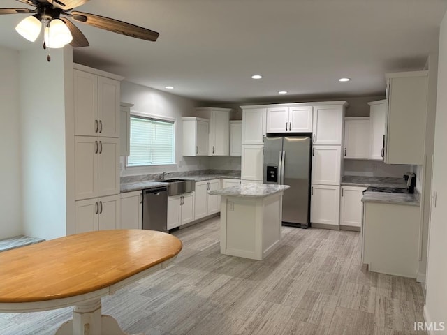 844 Ben Franklin St, Cloverdale, IN 46120 - kitchen with stainless steel appliances, a sink, a center island, light wood finished floors, and white cabinetry