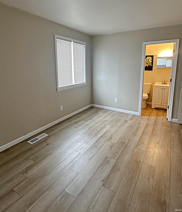 402 Sheridan St, Loogootee, IN 47553 - unfurnished bedroom featuring light wood-style flooring, baseboards, ensuite bath, and a sink