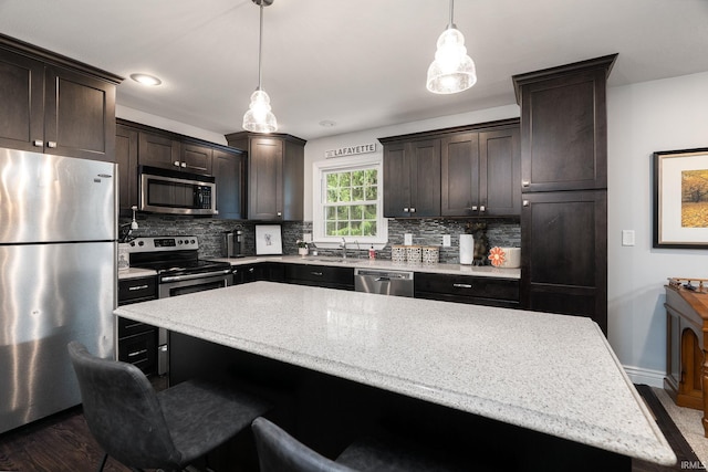 3599 Canterbury Dr, Lafayette, IN 47909 - kitchen featuring appliances with stainless steel finishes, tasteful backsplash, dark brown cabinetry, and a kitchen bar