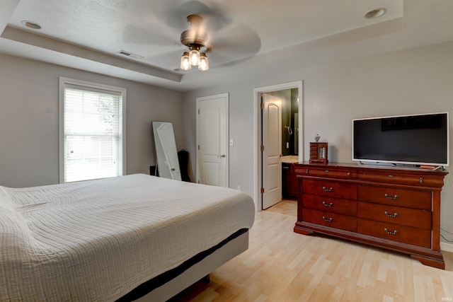 1444 Field Crest Ln, Jasper, IN 47546 - bedroom featuring a raised ceiling, light wood-type flooring, connected bathroom, and a ceiling fan