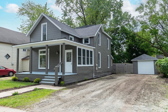 515 W Crawford St, Elkhart, IN 46514 - view of front facade with a porch, dirt driveway, a detached garage, an outdoor structure, and a shingled roof
