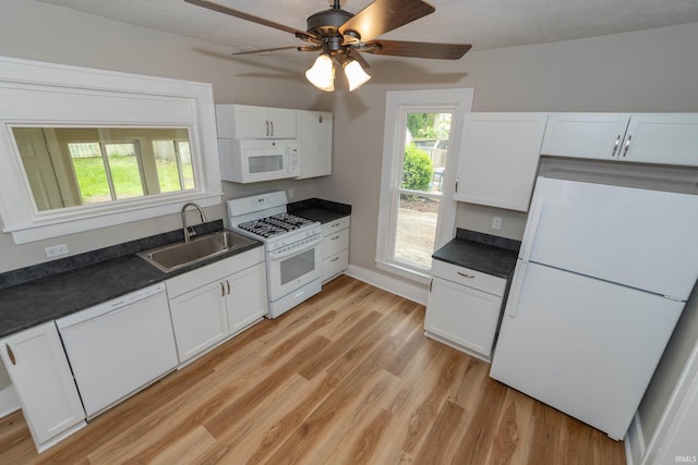 515 W Crawford St, Elkhart, IN 46514 - kitchen featuring white appliances, a sink, dark countertops, light wood-style flooring, and white cabinets