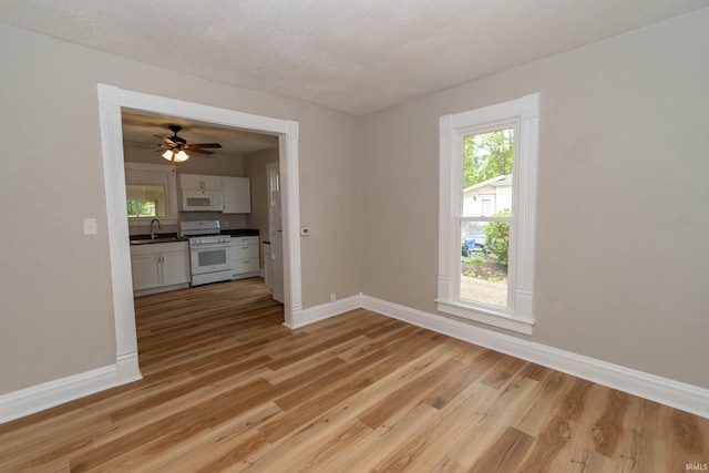 515 W Crawford St, Elkhart, IN 46514 - empty room featuring a sink, baseboards, light wood finished floors, and a ceiling fan