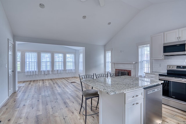 508 Polk St, Newburgh, IN 47630 - kitchen with appliances with stainless steel finishes, a kitchen bar, high vaulted ceiling, a brick fireplace, and light stone countertops
