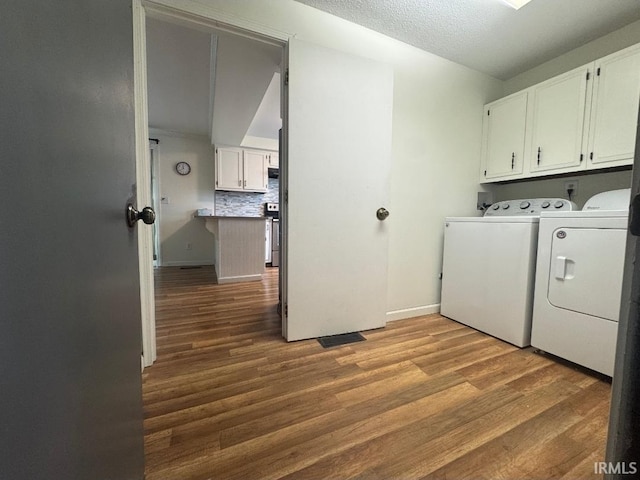 10704 Longwood Dr, Fort Wayne, IN 46845 - laundry area featuring cabinet space, washer and clothes dryer, wood finished floors, baseboards, and a textured ceiling