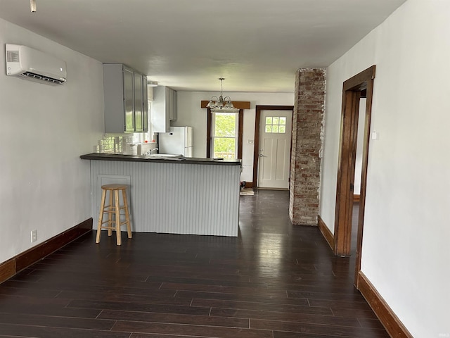 1338 Dewey St, Jasper, IN 47546 - kitchen featuring an AC wall unit, freestanding refrigerator, baseboards, dark wood-style floors, and a peninsula