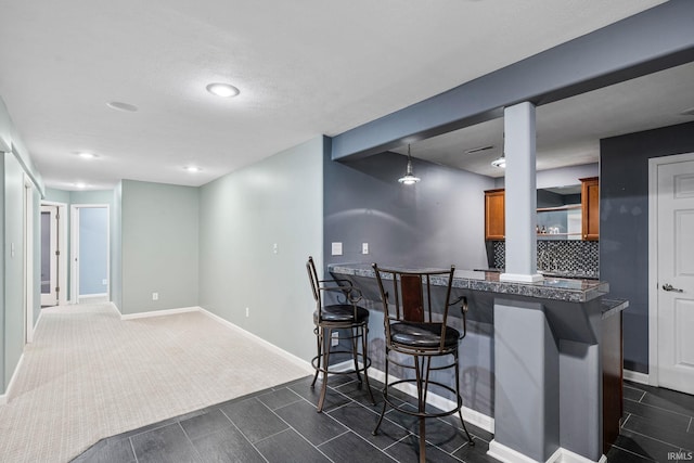 13849 Old Colony Dr, Granger, IN 46530 - kitchen with brown cabinets, dark countertops, a kitchen breakfast bar, a peninsula, and baseboards