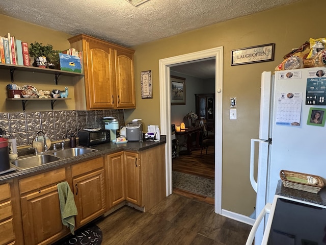 134 E Emerald St, Elkhart, IN 46514 - kitchen with freestanding refrigerator, a sink, dark wood-type flooring, dark countertops, and tasteful backsplash