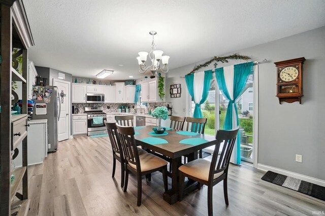 10221 Windsail Cv, New Haven, IN 46774 - dining area featuring a chandelier, light wood-style flooring, and baseboards