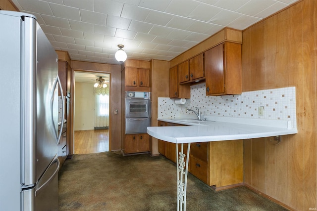 54188 Terrace Ln, South Bend, IN 46635 - kitchen featuring freestanding refrigerator, a sink, brown cabinetry, a peninsula, and light countertops