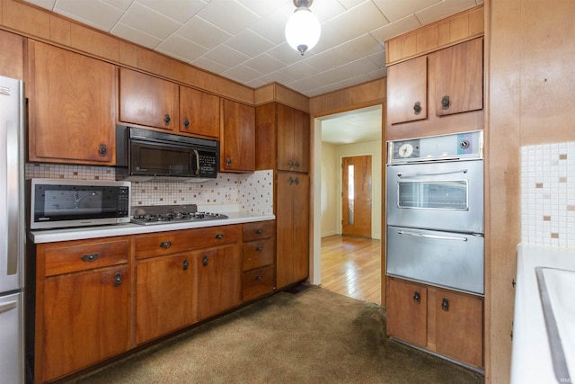 54188 Terrace Ln, South Bend, IN 46635 - kitchen featuring stainless steel appliances, brown cabinetry, light countertops, and tasteful backsplash