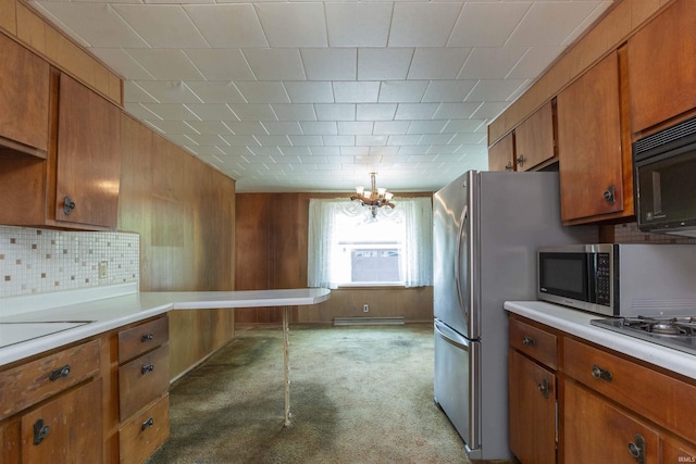 54188 Terrace Ln, South Bend, IN 46635 - kitchen with appliances with stainless steel finishes, brown cabinetry, a chandelier, light countertops, and backsplash