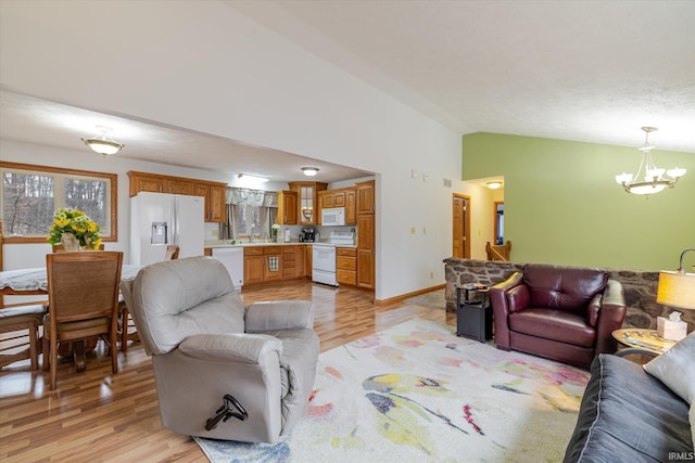 5959 W Delap Rd, Ellettsville, IN 47429 - living area featuring vaulted ceiling, a chandelier, light wood finished floors, and baseboards