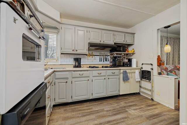 3902 Grayston Ave, Fort Wayne, IN 46806 - kitchen featuring light wood-style floors, tasteful backsplash, light countertops, under cabinet range hood, and gas stovetop