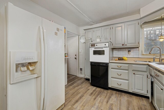 3902 Grayston Ave, Fort Wayne, IN 46806 - kitchen featuring white appliances, a sink, light wood finished floors, light countertops, and decorative backsplash