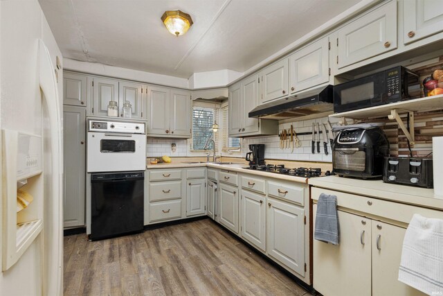 3902 Grayston Ave, Fort Wayne, IN 46806 - kitchen featuring under cabinet range hood, black appliances, wood finished floors, light countertops, and tasteful backsplash