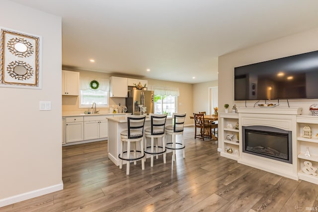 1804 W 14th St, Muncie, IN 47302 - kitchen with stainless steel fridge, a kitchen bar, wood finished floors, light countertops, and white cabinetry