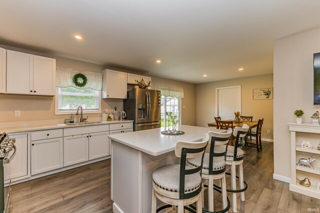 1804 W 14th St, Muncie, IN 47302 - kitchen with appliances with stainless steel finishes, a sink, a breakfast bar, dark wood-style flooring, and white cabinetry
