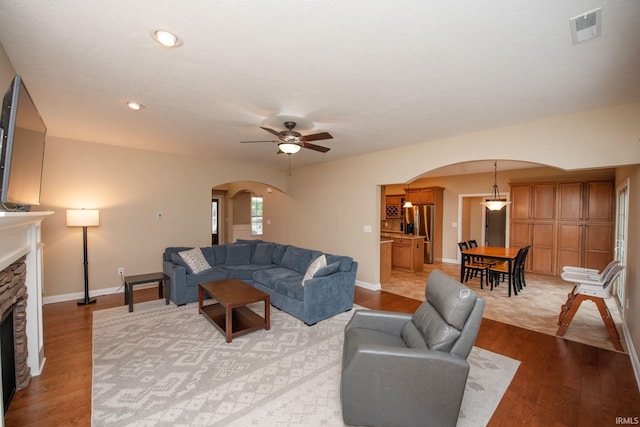 6118 Mackenzie Ct, West Lafayette, IN 47906 - living room with arched walkways, a stone fireplace, light wood-style flooring, ceiling fan, and recessed lighting