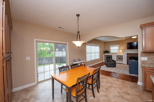 6118 Mackenzie Ct, West Lafayette, IN 47906 - dining room with arched walkways, a stone fireplace, plenty of natural light, and baseboards