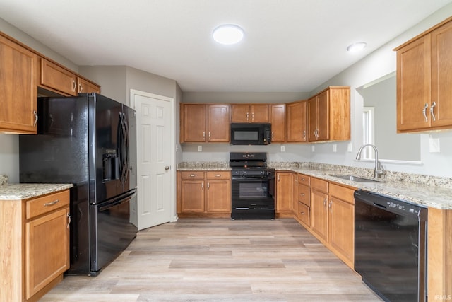 3827 Winter Raven Trl, Fort Wayne, IN 46818 - kitchen with black appliances, a sink, light wood finished floors, light stone countertops, and brown cabinets