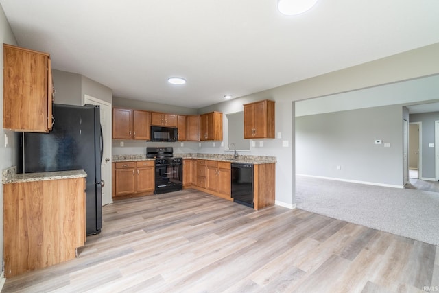 3827 Winter Raven Trl, Fort Wayne, IN 46818 - kitchen featuring black appliances, baseboards, light wood-style floors, brown cabinetry, and open floor plan