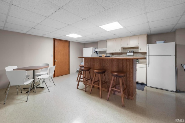 1437 W State Road 56th Rd, Jasper, IN 47546 - kitchen featuring freestanding refrigerator, under cabinet range hood, a kitchen bar, a drop ceiling, and a center island