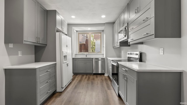 524 Byron St, Huntington, IN 46750 - kitchen featuring stainless steel appliances, gray cabinetry, wood finished floors, light countertops, and a sink