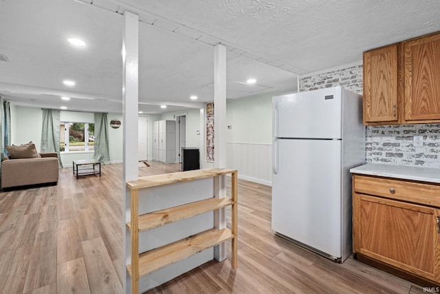 1310 Oak Ave, Lafayette, IN 47905 - kitchen with freestanding refrigerator, light wood-style floors, open floor plan, brown cabinetry, and a wainscoted wall