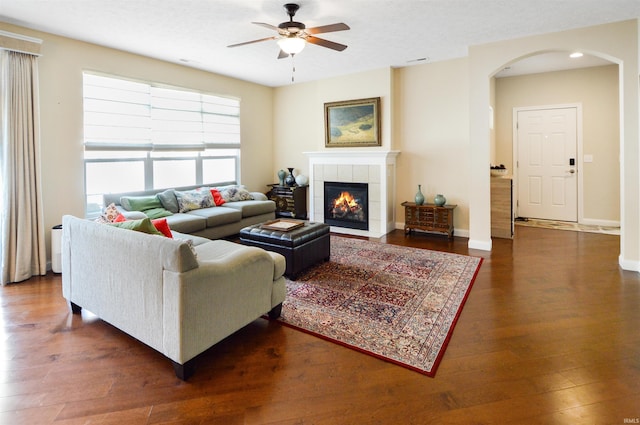 1632 Solemar Dr, West Lafayette, IN 47906 - living room with arched walkways, ceiling fan, a tiled fireplace, and dark wood-style floors