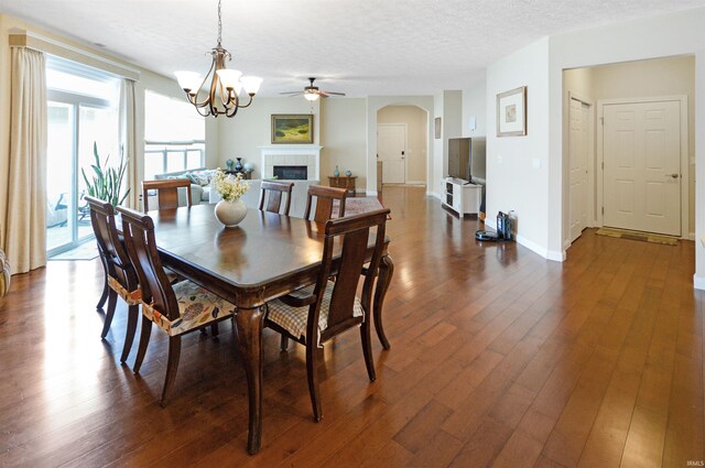1632 Solemar Dr, West Lafayette, IN 47906 - dining space featuring arched walkways, a tiled fireplace, dark wood-style floors, a ceiling fan, and a textured ceiling