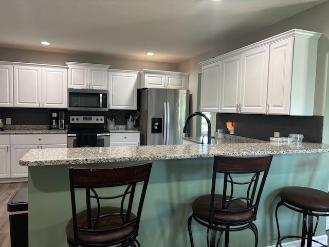 1264 W Greenbriar Dr, Washington, IN 47501 - kitchen with stainless steel appliances, white cabinetry, a peninsula, recessed lighting, and wood finished floors