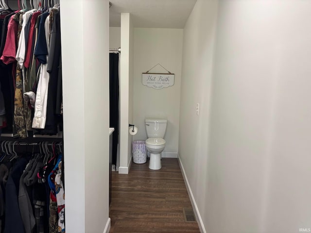 1264 W Greenbriar Dr, Washington, IN 47501 - bathroom featuring toilet, wood finished floors, a walk in closet, baseboards, and curtained shower